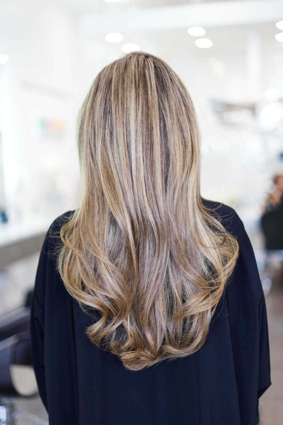 Long, wavy, blonde hair styled in a salon setting, viewed from the back.